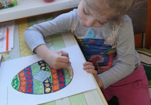 Wiktoria maluje kredkami kolorowankę "Jajko"